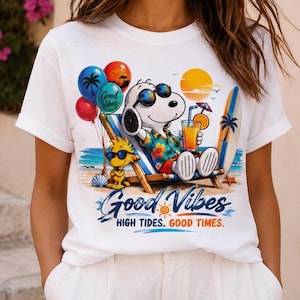 May include: A white t-shirt featuring a graphic of a cartoon dog wearing sunglasses and a floral shirt, relaxing in a beach chair with a drink. The design includes balloons, a surfboard, and the text Good Vibes HIGH TIDES. GOOD TIMES.