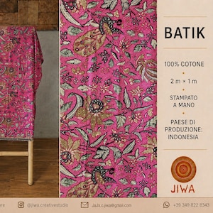May include: A vibrant pink batik fabric featuring a detailed floral and peacock pattern. The textile is 100% cotton, measuring 2 metres by 1 metre, and is hand-printed in Indonesia. The fabric is displayed draped over a wooden frame.