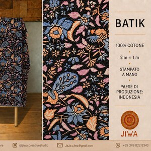 Puede incluir: Una pieza rectangular de tela negra con un patrón floral batik en tonos azules, naranjas y rosas. El texto en la imagen dice BATIK, 100% COTONE, 2 m x 1 m, STAMPATO A MANO, PAESE DI PRODUZIONE: INDONESIA y el nombre de la marca JIWA.