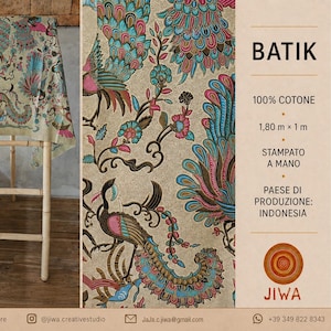 Op de afbeelding: Een beige batikstof met een kleurrijk pauwenpatroon met blauwe, roze en bruine details. De stof meet 1,80 m bij 1 m en is 100% katoen. De tekst op de afbeelding bevat BATIK, 100% COTTON, 1,80 m x 1 m, HAND-PRINTED en JIWA.