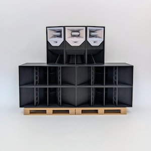 Peut inclure: Un empilement de caissons de haut-parleurs noirs disposés sur deux rangées, avec trois enceintes à pavillon blanc au-dessus et quatre enceintes rectangulaires plus grandes en dessous, reposant sur deux socles en bois clair.