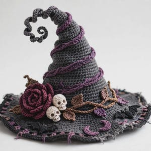 May include: A dark gray crocheted witch hat featuring a curled tip, a purple yarn spiral, a large dark red crocheted rose, two small white skulls, brown crocheted vines with leaves, and small black crocheted bats and crescent moon shapes.