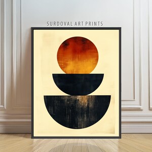 May include: Abstract art print featuring a black frame. The artwork displays a large, orange and red circle above two black, semi-circular shapes. The background is a light beige color, and the text "SURDOVAL ART PRINTS" is at the top.