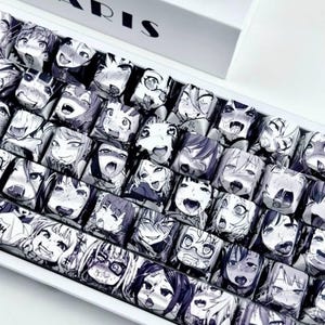 May include: A mechanical keyboard featuring a white frame and custom keycaps printed with a repeating black and white manga-style graphic pattern of various anime character faces with expressive, open-mouthed facial expressions.