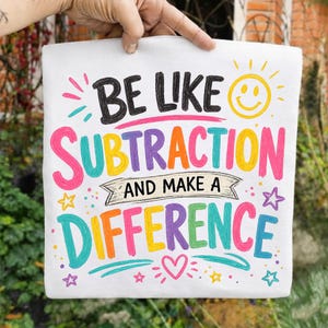 May include: A white t-shirt featuring colourful text that reads BE LIKE SUBTRACTION AND MAKE A DIFFERENCE. The design includes a yellow smiley face, pink, orange, purple, and teal lettering, along with small star and heart graphic accents.