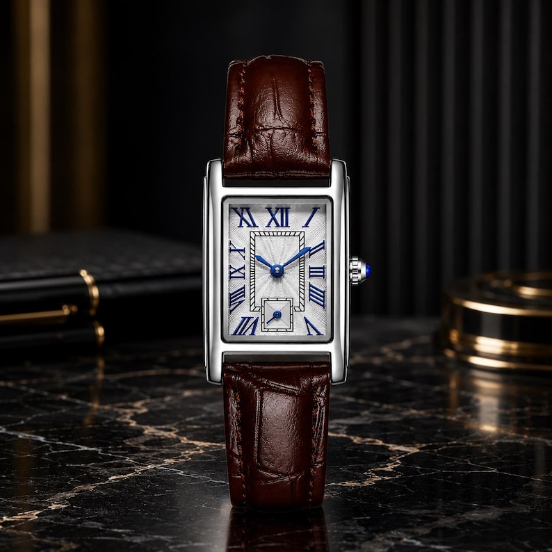 May include: A rectangular wristwatch with a silver-tone case and a dark brown crocodile-embossed leather strap. The white dial features blue Roman numeral hour markers, blue hands, a central textured rectangular pattern, and a small sub-dial at the bottom.
