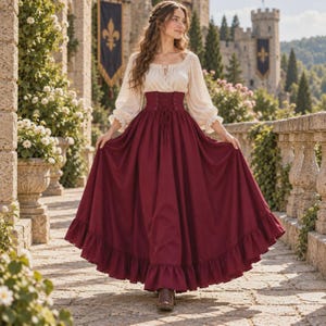 May include: A long-sleeved cream-colored blouse with a scoop neckline and a deep red floor-length skirt featuring a high-waisted corset-style bodice with lace-up detailing and a ruffled hemline, creating a two-piece ensemble.