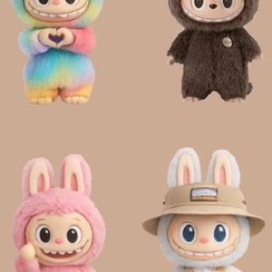 May include: Four plush rabbit-like figures with smiling faces and large eyes. One is rainbow-colored, one brown, one pink, and one wearing a hat and overalls. The figures have bunny ears and are on a tan background.