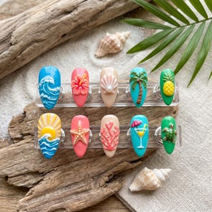 May include: A set of ten artificial nails with a summer theme. Designs include waves, hibiscus flowers, seashells, palm trees, pineapples, a sunset, starfish, coral, a cocktail, and a turtle. The nails are displayed on a clear stand.