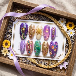 May include: A set of ten press-on nails featuring intricate hand-painted designs inspired by a fairy tale. The nails display motifs including a tall tower, a golden sun, a green chameleon, braided hair, floating lanterns, and floral accents.