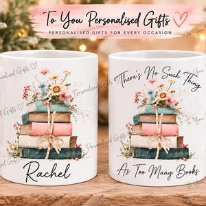 May include: Two white ceramic mugs featuring a stack of five colourful books topped with a bouquet of wildflowers. The left mug displays the name Rachel in black script, while the right mug features the text There's No Such Thing As Too Many Books.
