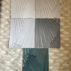 May include: Five rectangular prints featuring a radiating fan-like pattern of pleated lines. The top left is white, the top right is light beige, the middle left is light gray, the middle right is dark gray, and the bottom is teal and gold.