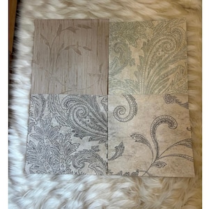 Puede incluir: Cuatro muestras de papel tapiz cuadradas dispuestas en una cuadrícula. La superior izquierda presenta una textura de fibra vegetal marrón claro con hojas. Los otros tres cuadrados muestran tonos beige y gris con motivos de cachemira y flores.