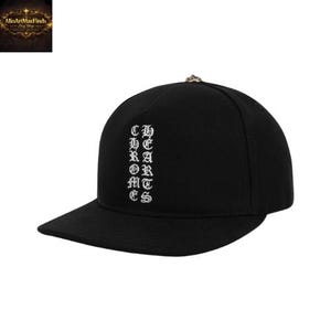 May include: A black baseball cap featuring a flat brim and a structured crown. The front panel displays the text CHROME HEARTS embroidered in white using a gothic-style font. A small metallic button is centered at the top of the cap crown.