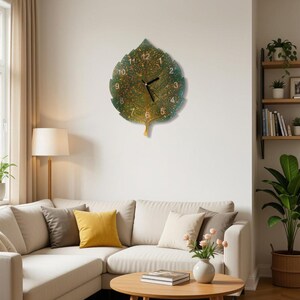 May include: A leaf-shaped wall clock featuring a green and gold speckled surface with black clock hands and white numerals from one to twelve arranged in a circular pattern on the face of the leaf.