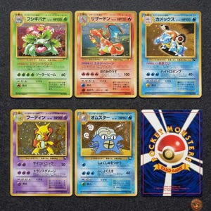 Puede incluir: Una colección de cinco cartas coleccionables japonesas con Venusaur, Charizard, Blastoise, Alakazam y Omastar, junto con el reverso de una carta que muestra el logotipo de Pocket Monsters Card Game con un gráfico de Poké Ball rojo y blanco.