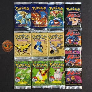 May include: A collection of twelve sealed Pokémon trading card booster packs arranged in a grid. The packs feature various character illustrations including Blastoise, Charizard, Venusaur, Zapdos, Lapras, Aerodactyl, Scyther, Flareon, and Jigglypuff.