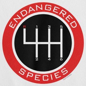 May include: A white t-shirt featuring a red and black graphic of a six-speed manual transmission gear shift pattern. The words "ENDANGERED SPECIES" are in a red ring around the gear shift.