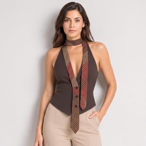 May include: A dark brown halter-style waistcoat featuring a deep V-neckline and a long, integrated necktie. The tie is patterned with small white dots on a red and brown background, featuring three visible buttons down the centre of the front panel.