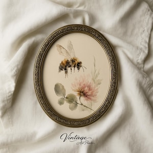 Peut inclure: Impression d'art encadrée ovale avec une aquarelle d'une abeille près d'une fleur rose. L'abeille a des rayures marron et jaune. Le cadre est doré avec un design orné. Les mots "Vintage Art Prints" sont en bas.