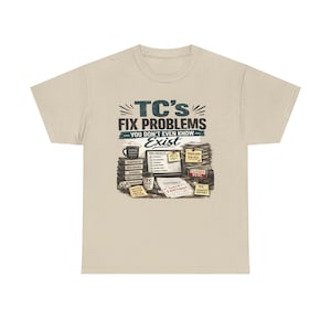 May include: A beige t-shirt with a graphic that reads "TC's FIX PROBLEMS YOU DON'T EVEN KNOW Exist." The graphic includes a coffee cup, stacks of papers, and various office-related items. The shirt is made of a soft material.