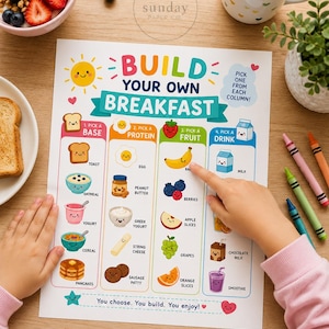 以下が含まれることがあります： Build Your Own Breakfastというタイトルの白い紙のアクティビティシート。Base、Protein、Fruit、Drinkとラベル付けされた4つの列に、食べ物のカラフルなイラストが整理されています。シートには食べ物に描かれた漫画の顔とテキストが含まれています。