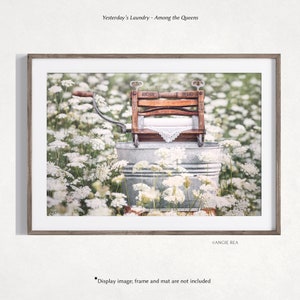May include: A vintage wooden wringer washing machine with the words "Anchor Brand" on it, sitting in a galvanized metal tub. The machine is surrounded by white flowers.