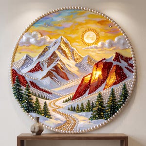 May include: A circular wall art piece featuring a textured mountain landscape painting embellished with white pearls along the border and within the scene. The artwork depicts snow-capped peaks, a golden sun, and evergreen trees in a winter setting.