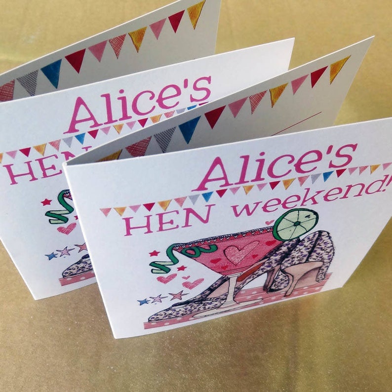 May include: Three pink and white cards with a colorful triangle border. The cards have the text "Alice's HEN weekend!" and a pink cocktail glass with a lime wedge and a high heel shoe with a leopard print design.