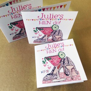 May include: Three white cards with pink and green illustrations of a cocktail glass with a lime wedge and two high-heeled shoes. The text on the cards reads "Julie's Hen do!"
