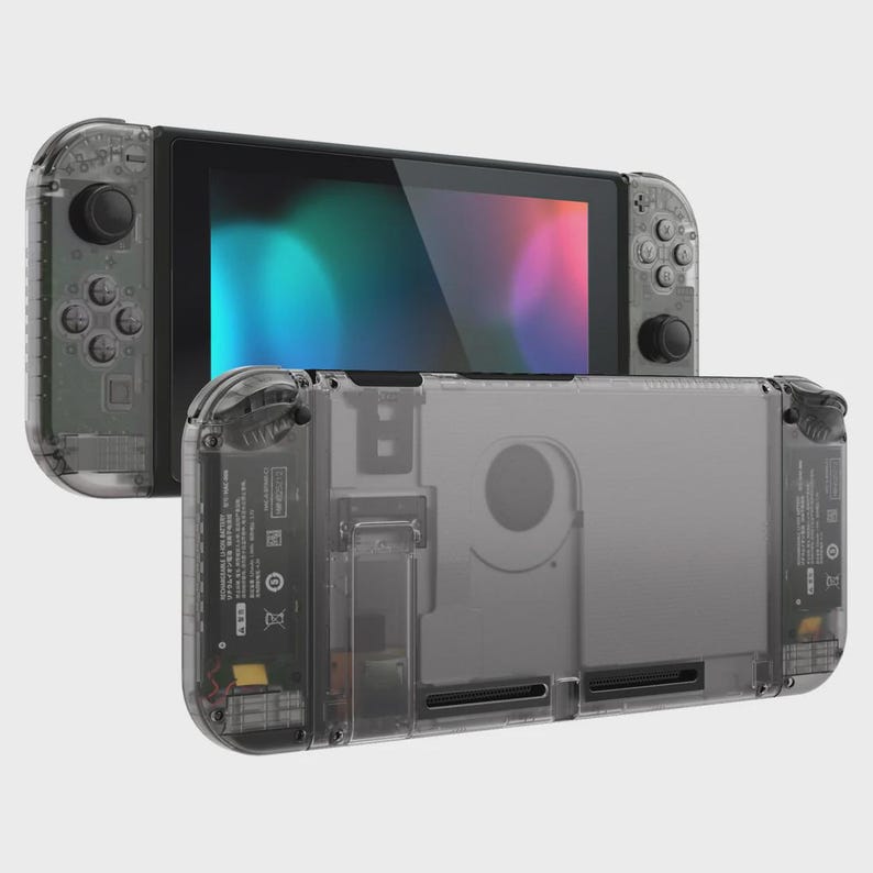 May include: A handheld video game console featuring a transparent dark gray shell. The device includes a central screen displaying a colorful gradient and two detachable side controllers with black buttons, joysticks, and a directional pad.