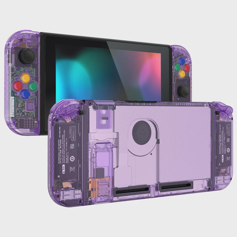 May include: A handheld gaming console featuring a transparent purple shell that reveals internal components. The device includes a black screen, two detachable controllers with multi-colored buttons, and a rear view showing the battery and cooling fan.