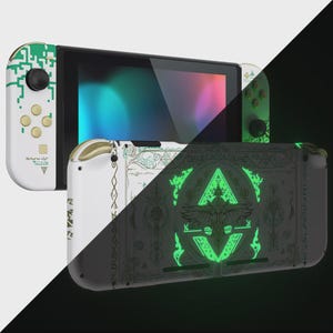 May include: A handheld gaming console featuring white and green digital circuit patterns on the controllers and a black back panel adorned with intricate, glowing green geometric symbols and ornate line art designs across the surface.
