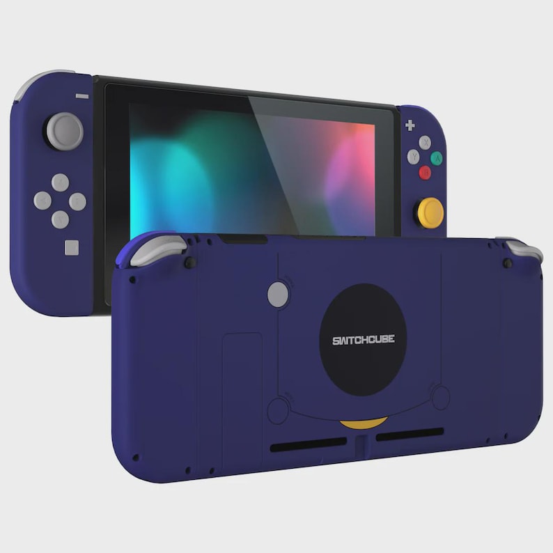 May include: A handheld gaming console in deep purple with a black screen, featuring a yellow analog stick, grey buttons, and a rear casing labeled SWITCHCUBE. The device includes a directional pad, four colored action buttons, and shoulder triggers.
