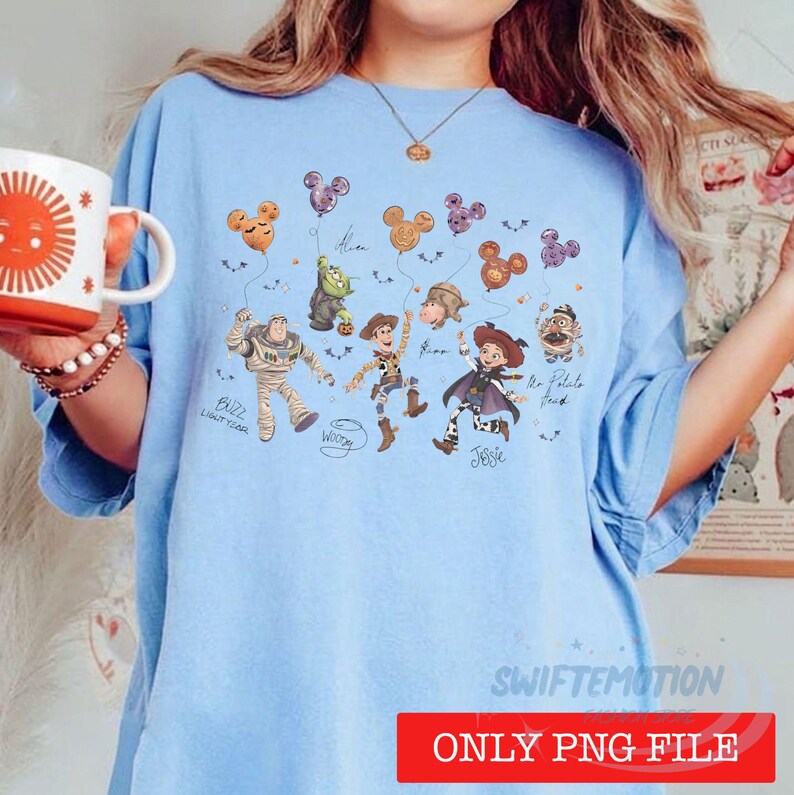 May include: A light blue t-shirt featuring a graphic print of various animated characters from the Toy Story franchise, including Buzz Lightyear, Woody, and Jessie, holding Mickey Mouse-shaped balloons, with character names written in cursive script.