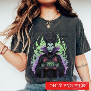 K&ouml;nnte beinhalten: Ein anthrazitfarbenes T-Shirt mit einer Grafik einer gr&uuml;nh&auml;utigen Figur mit H&ouml;rnern, die ein schwarzes Gewand mit violettem Kragen tr&auml;gt. Die Figur h&auml;lt ein Schild mit der Aufschrift 1959 vor einem Hintergrund aus gr&uuml;nen Flammen und einer Messlatte.