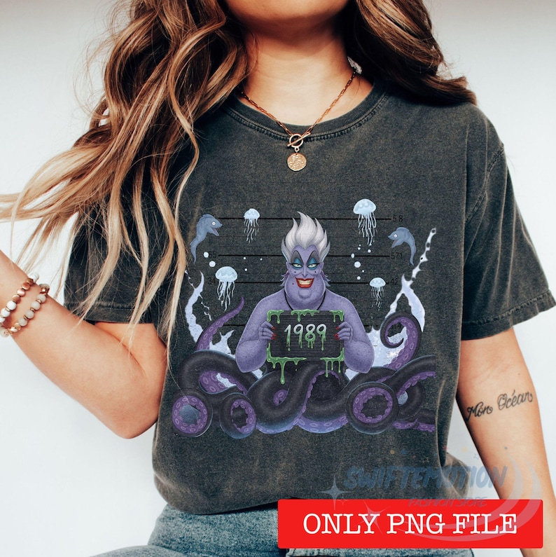 May include: A charcoal gray t-shirt featuring a graphic of a purple-skinned character with white hair holding a sign that reads 1989. The design includes purple tentacles, jellyfish, and a height chart background with numbers 5'8, 5'4, 5'0, and 4'8.