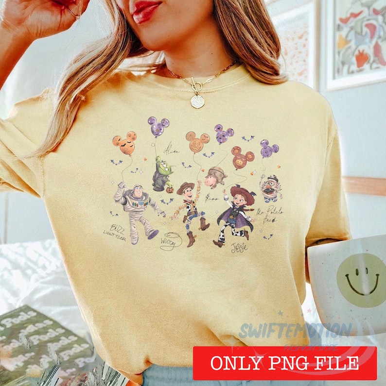 May include: A pale yellow t-shirt featuring a graphic print of Toy Story characters including Buzz Lightyear, Woody, Jessie, and Mr. Potato Head holding Mickey-shaped balloons. The design includes handwritten-style text labels for each character.