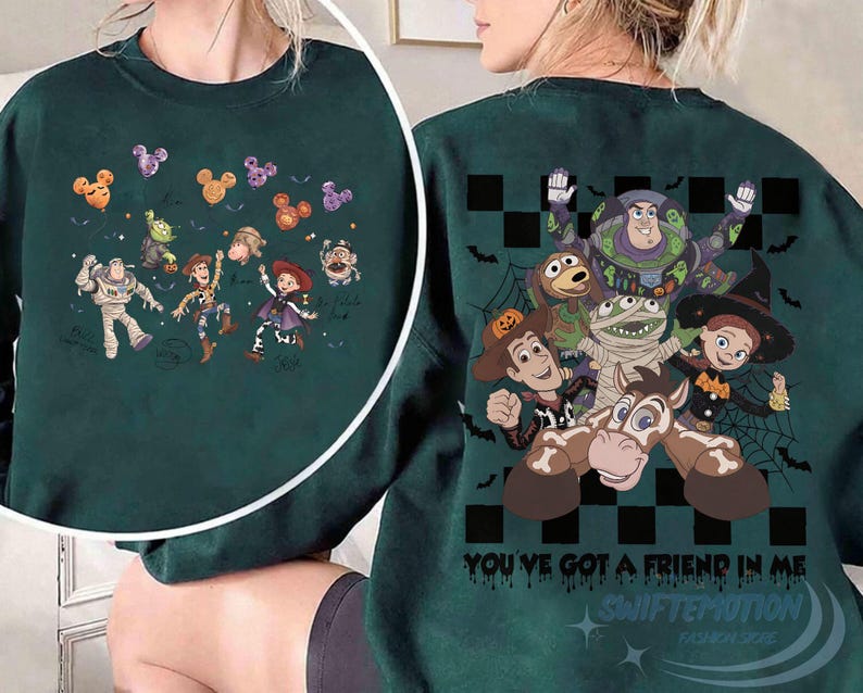 May include: A dark green crewneck sweatshirt featuring a graphic print of Toy Story characters in Halloween costumes. The design includes Buzz Lightyear, Woody, Jessie, and others with spiderwebs, bats, and the text "YOU'VE GOT A FRIEND IN ME".