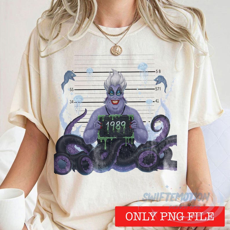 May include: A cream-colored t-shirt featuring a graphic of a purple sea witch with tentacles, positioned against a mugshot height chart background. The character holds a sign with the text 1989, surrounded by small blue jellyfish and fish.