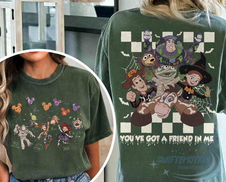 May include: A dark green t-shirt featuring Toy Story characters in Halloween costumes. The back displays Buzz Lightyear, Woody, Jessie, and others with the text "YOU'VE GOT A FRIEND IN ME". The front shows the characters holding Mickey-shaped balloons.