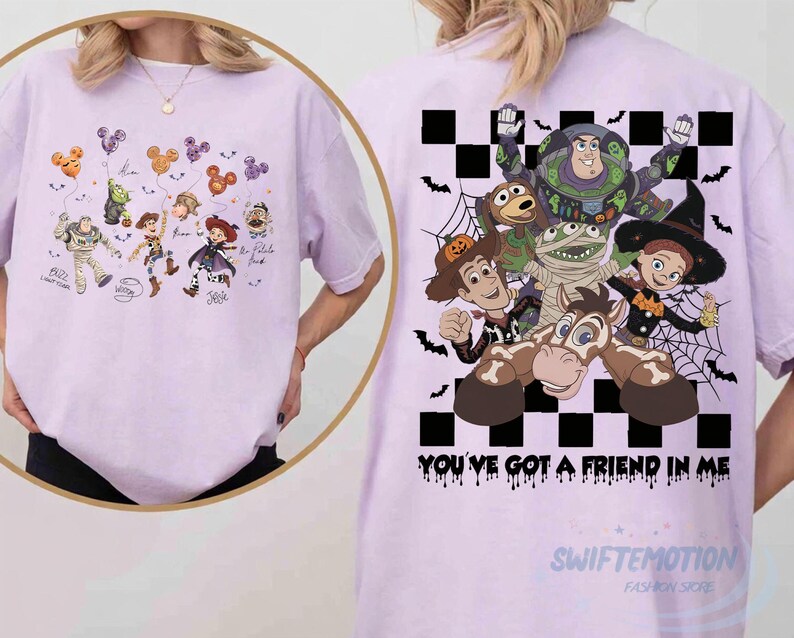May include: A light purple t-shirt featuring a large graphic on the back of Toy Story characters in Halloween costumes against a black and white checkered background with the text "YOU'VE GOT A FRIEND IN ME" and a smaller front chest graphic.