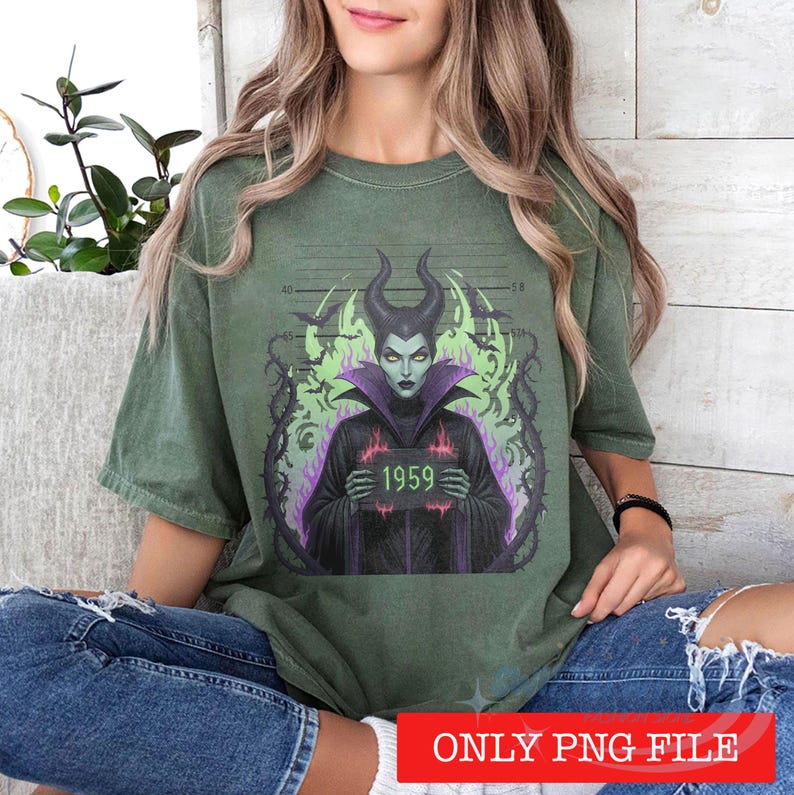 K&ouml;nnte beinhalten: Ein olivgr&uuml;nes Kurzarm-T-Shirt mit einem Grafikdruck einer geh&ouml;rnten Figur mit gr&uuml;ner Haut und violettem Kragen. Die Figur h&auml;lt ein Schild mit der Aufschrift 1959 vor einem Hintergrund aus schwarzen Dornenranken, Flederm&auml;usen und gr&uuml;nen Flammen.