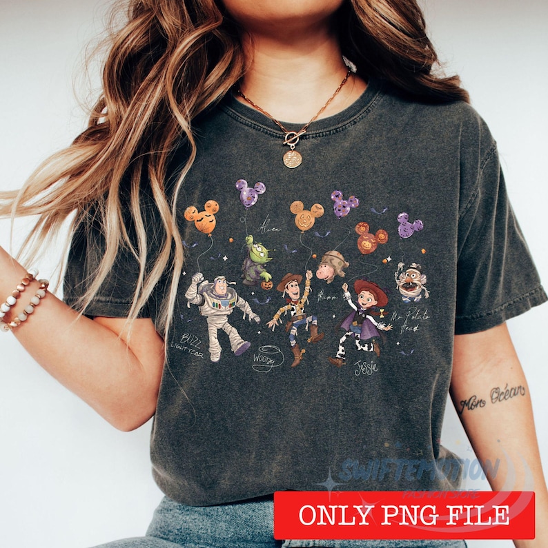 May include: A charcoal gray t-shirt featuring a graphic print of Toy Story characters including Buzz Lightyear, Woody, and Jessie. The design includes Mickey-shaped balloons, stars, and character names written in a cursive script font.