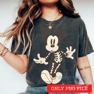 May include: Dark gray t-shirt featuring a skeleton Mickey Mouse design. The graphic shows Mickey's skeleton overlaid on his classic form. The shirt has a vintage, worn look. The text "ONLY PNG FILE" is at the bottom.