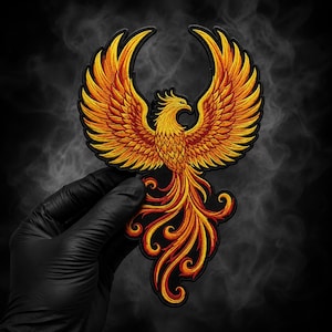 May include: Embroidered patch featuring a phoenix design. The patch showcases a vibrant color palette of yellow, orange, and red, with intricate detailing. The phoenix is depicted with outstretched wings and flowing tail feathers, set against a black background.