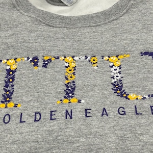May include: Gray sweatshirt with a floral design spelling out "TTU" and the text "Golden Eagles" underneath.