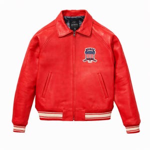 Puede incluir: Una chaqueta de cuero rojo brillante con cuello cl&aacute;sico, cremallera frontal completa y pu&ntilde;os y dobladillo acanalados con rayas blancas. Un parche en el pecho izquierdo muestra el texto AVIREX sobre un gr&aacute;fico de escudo con dise&ntilde;o de bandera.