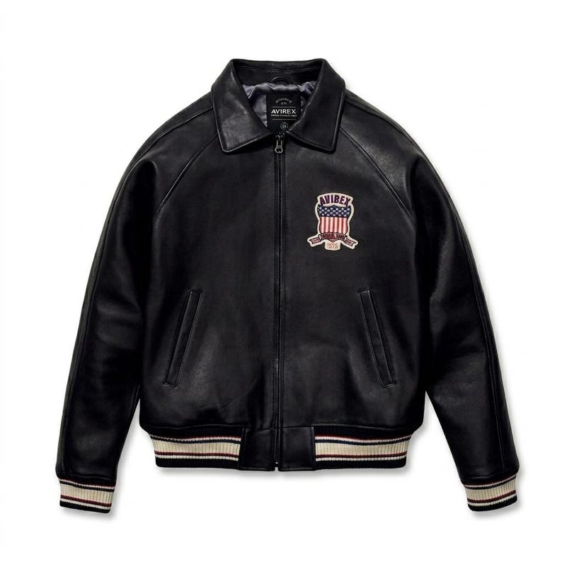 May include: A black leather jacket with a full-length front zipper, a classic collar, and ribbed cuffs and hem featuring white and maroon stripes. A patch on the left chest displays the text AVIREX above a shield with an American flag design.