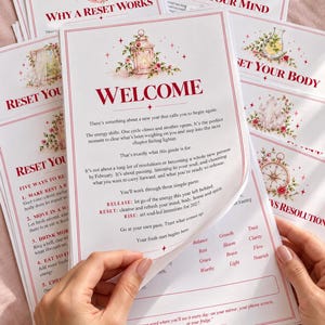 Peut inclure: Une pile de guides en papier blanc avec du texte rouge et des illustrations florales. La page supérieure présente le titre Welcome, suivi d'un texte sur la réinitialisation de la nouvelle année, trois parties et une liste de mots.